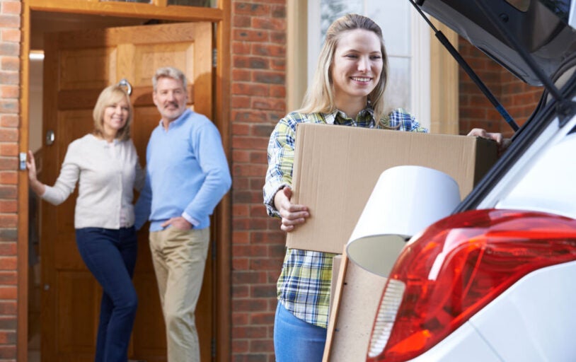 Girl packing her car while parents watch from doorway
