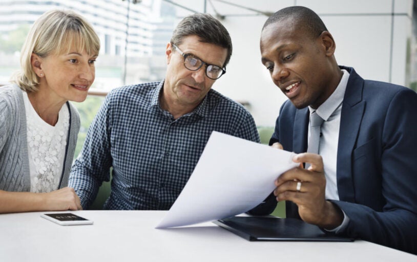 Three people at a table with a document