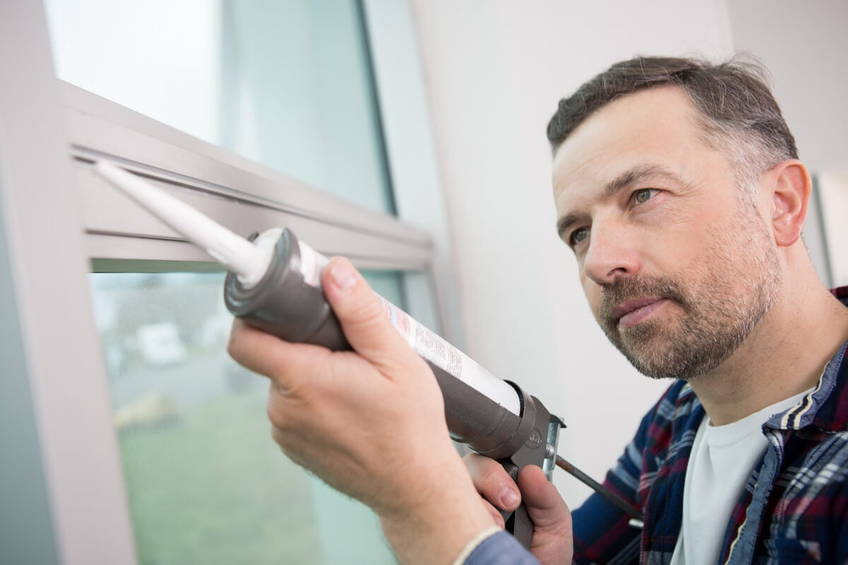 Man caulking his window