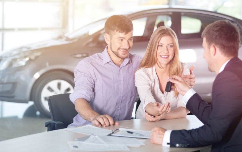 Young couple getting keys to a new car