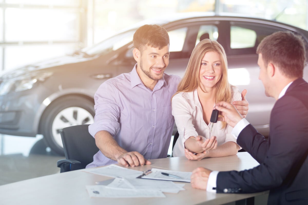 Young couple getting keys to a new car