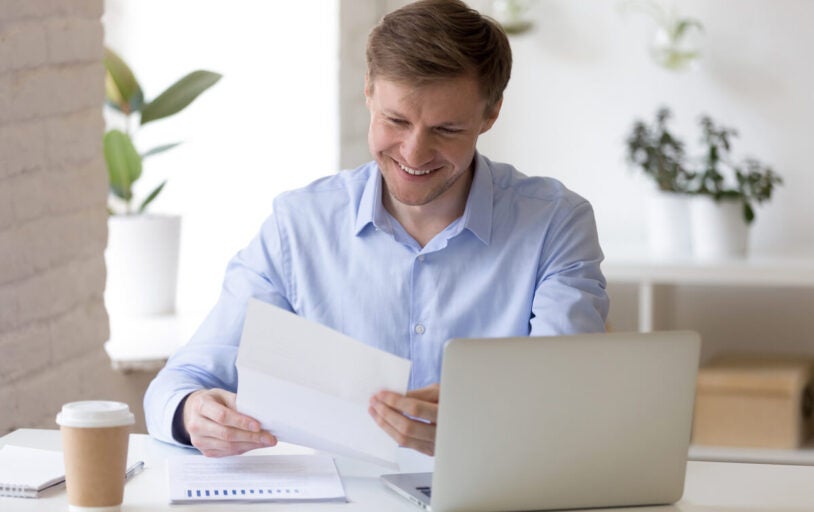 Man sitting at desk with paper and laptop