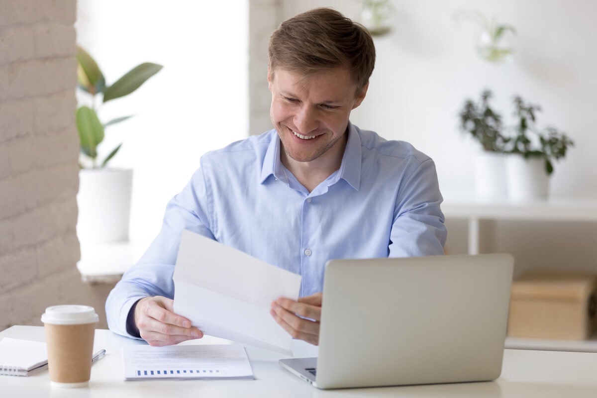 Man sitting at desk with paper and laptop