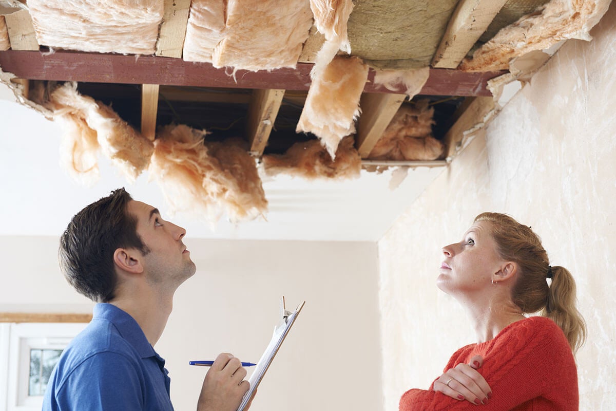 Two people looking at a damaged ceiling