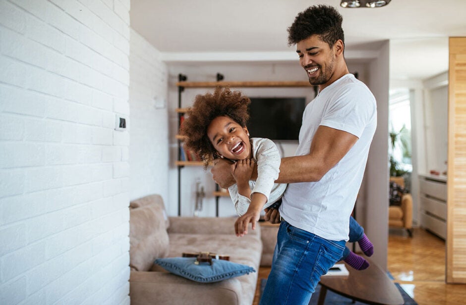 Dad lifting child in living room