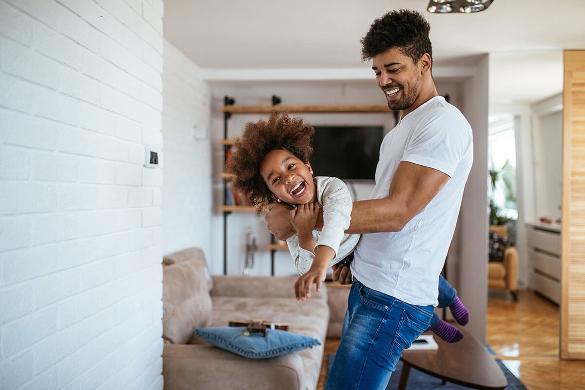 Dad lifting child in living room