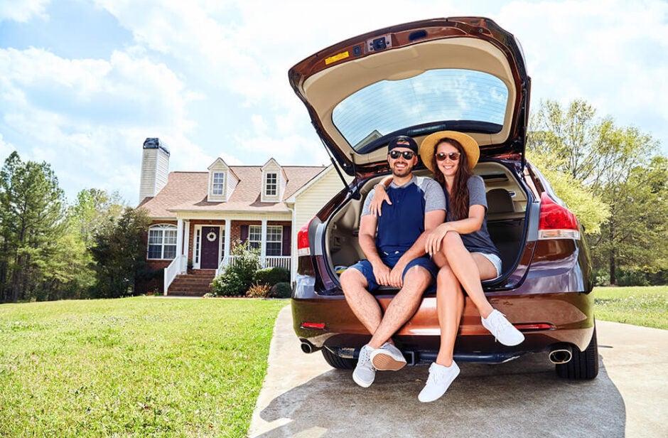 Couple in the back of a automobile in front of house