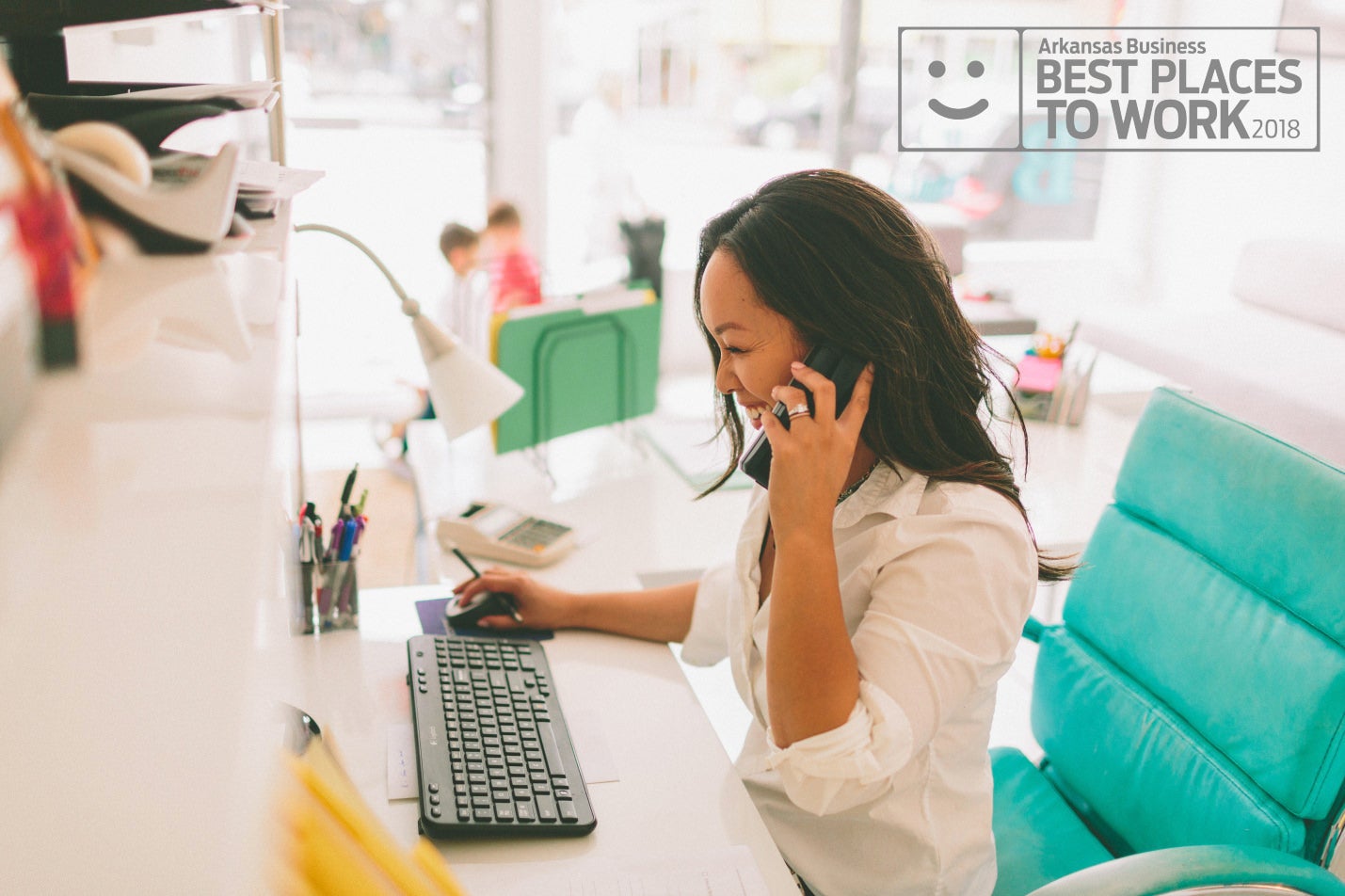 Women on a phone in front of a computer, Arkansas Business Best Places to Work 2018
