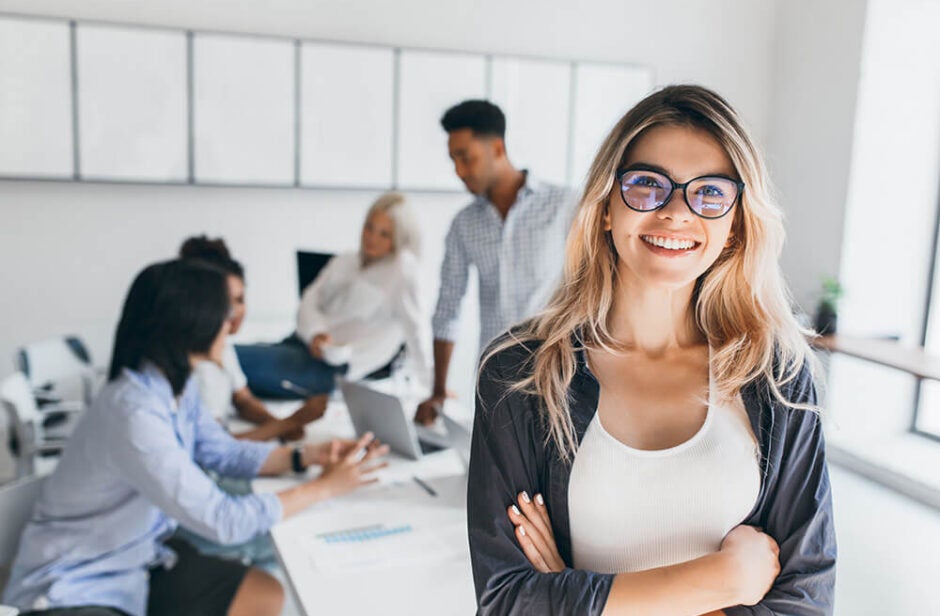 Woman smiling in conference room with four employees in the background