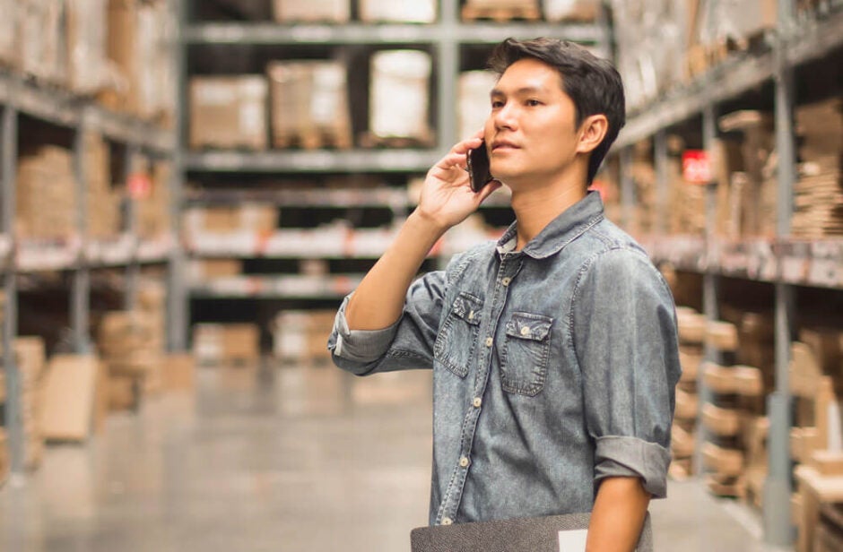 Man standing in warehouse talking on a cell phone