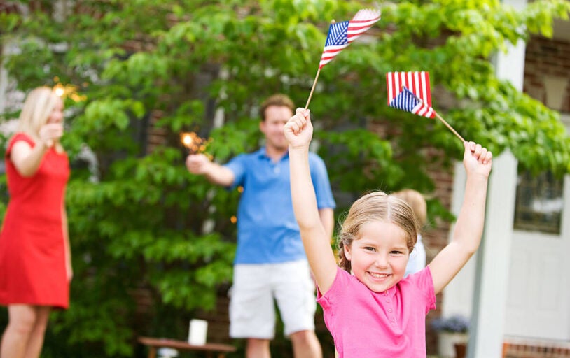 Little girl waving two small American flags