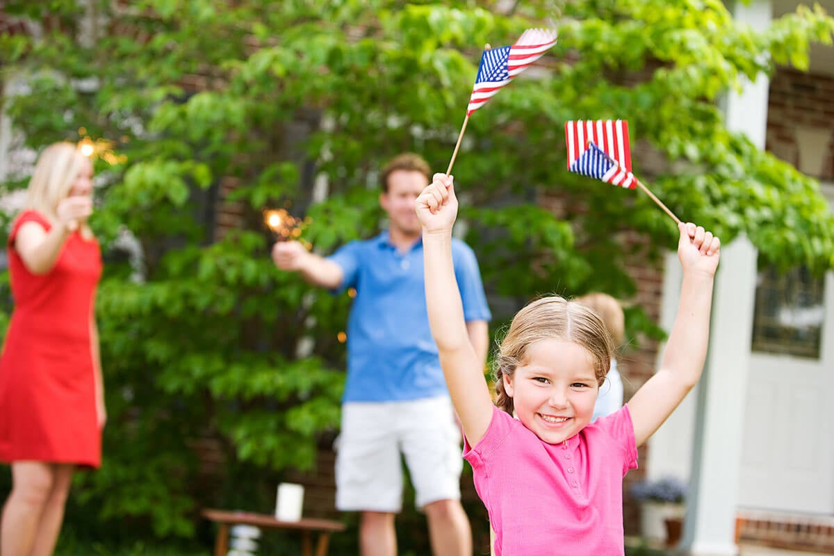 Little girl waving two small American flags