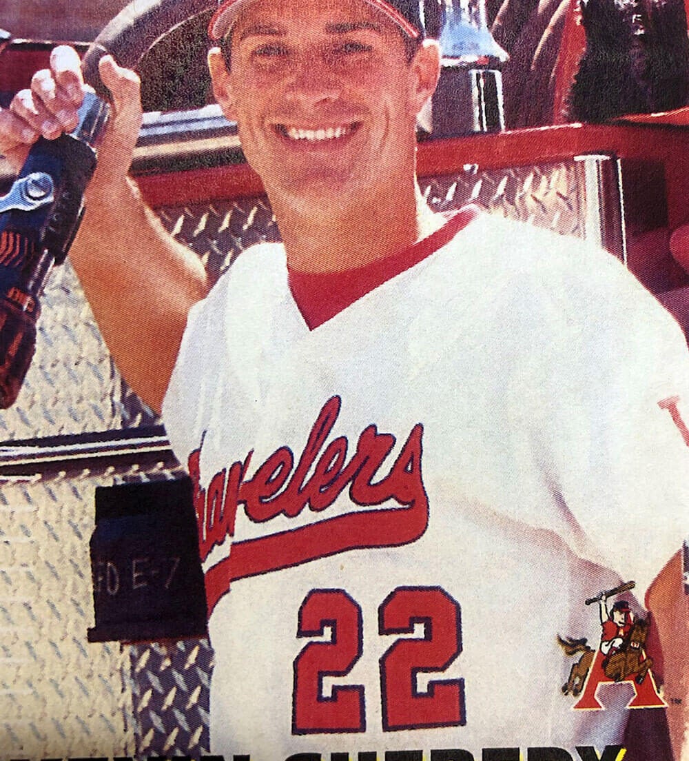 Man in baseball uniform by firetruck