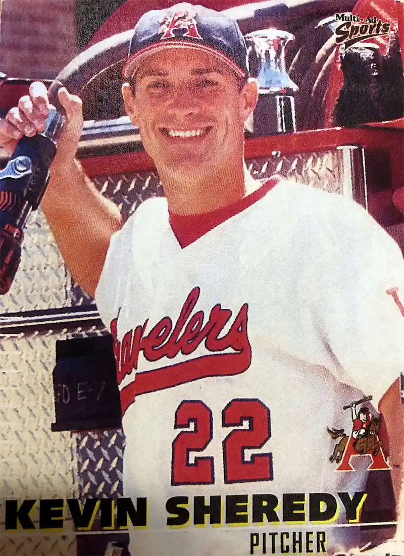 Man in baseball uniform by firetruck