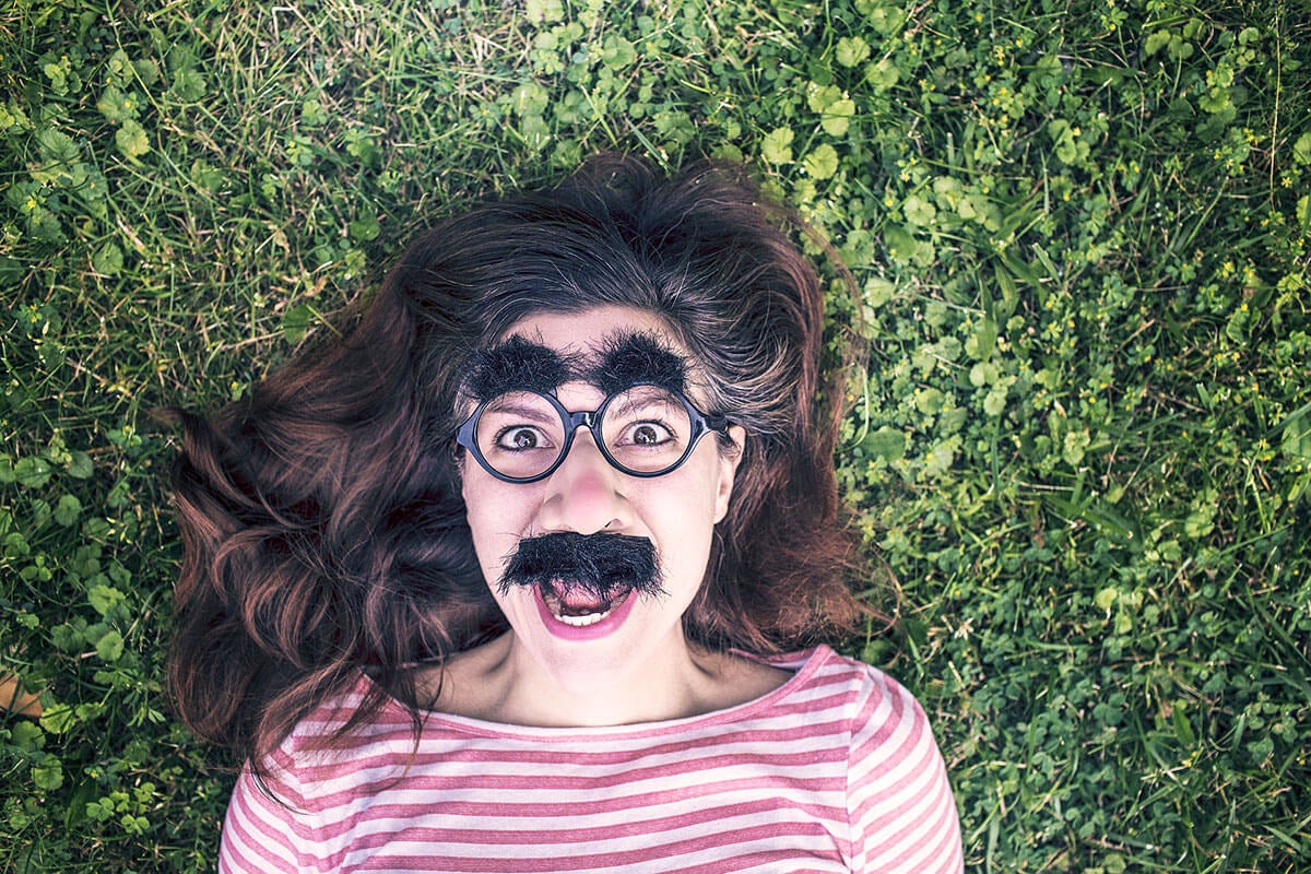 Woman laying in grass with funny glasses on