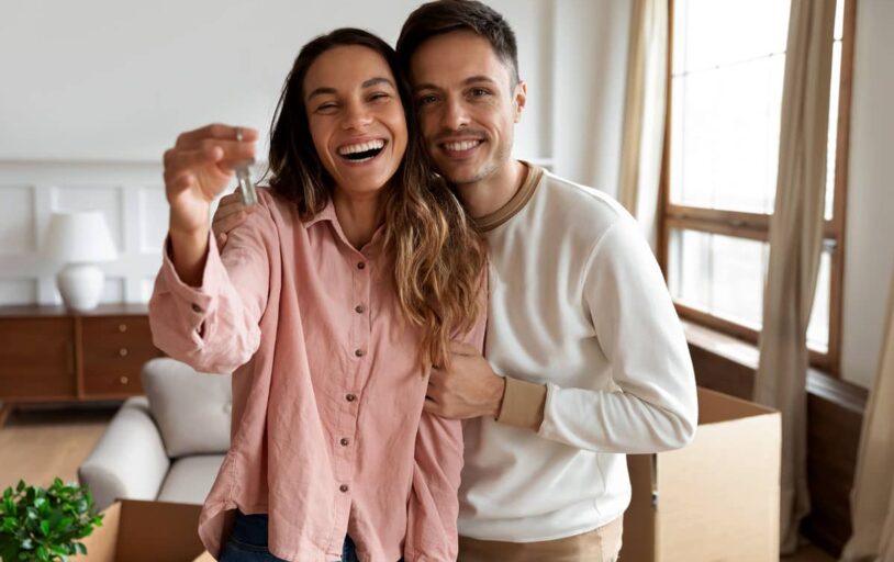 Young woman and man in a room holding keys to new home