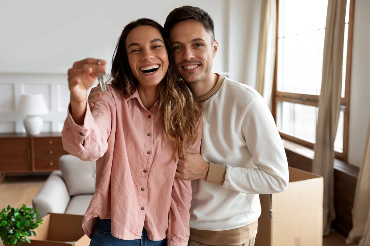 Young woman and man in a room holding keys to new home