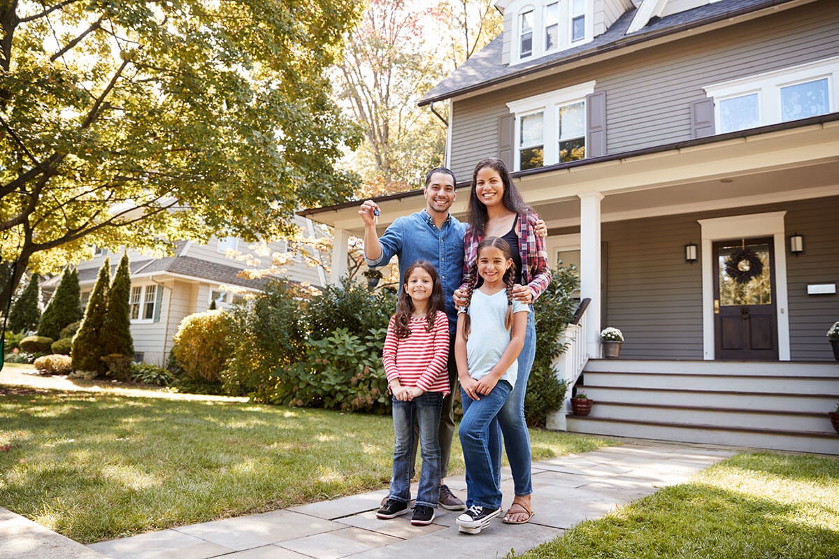 Young family standing in front of their new home