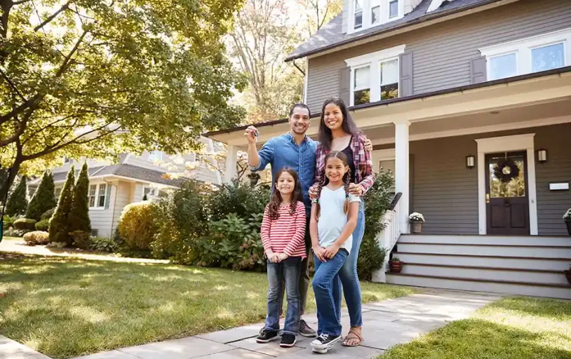 Young family standing in front of their new home