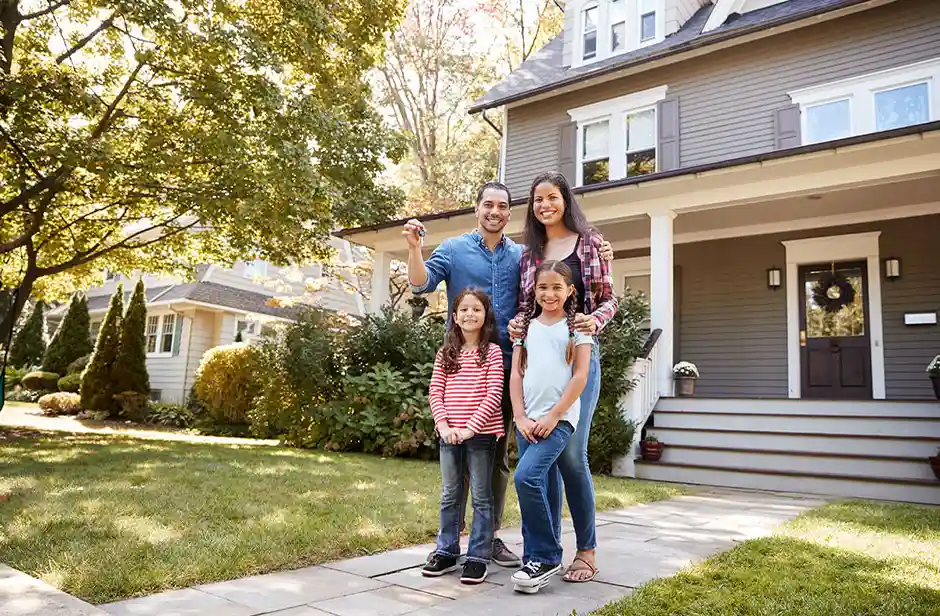 Young family standing in front of their new home