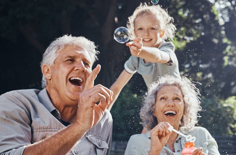 Grandparents and grandchild outside blowing and popping bubbles