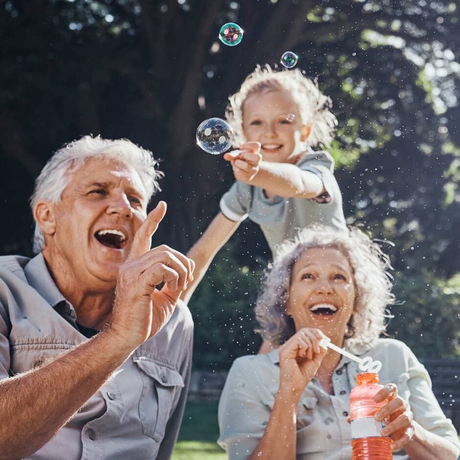 Grandparents and grandchild outside blowing and popping bubbles