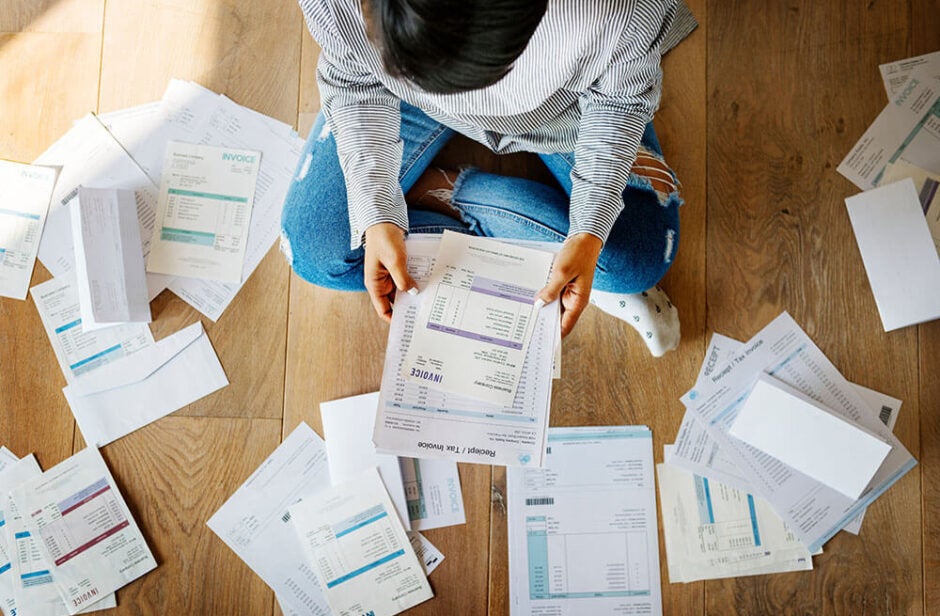 Stressed woman looking at a pile of bills in her home