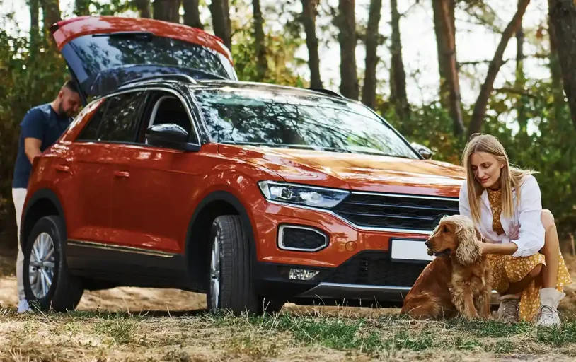 Couple and dog with car